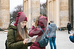 A beautiful tourist girl uses a tablet in the square next to the Brandenburg Gate in Berlin.