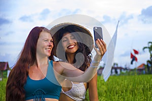 Beautiful tourist girls taking girlfriends selfie together with mobile phone in rice field nature landscape smiling enjoying