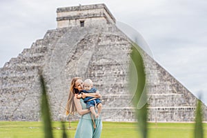Beautiful tourist woman and her son baby observing the old pyramid and temple of the castle of the Mayan architecture