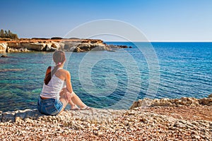 Beautiful tourist woman on the old castle on Mediterranean sea coast. Paphos, Cyprus. Bright sunset light