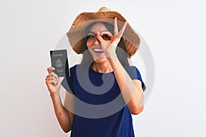 Beautiful tourist woman wearing hat holding USA passport over isolated white background with happy face smiling doing ok sign with