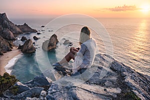 Beautiful tourist women enjoying sunset at Praia da Ursa Beach. Surreal scenery of Sintra, Portugal. Atlantic Ocean