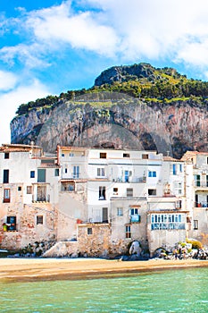 Beautiful traditional houses on the coast of Tyrrhenian sea in Cefalu, Sicily, Italy. Behind the buildings magnificent rock