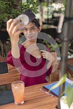 A beautiful trans woman takes a selfie on a sunny afternoon as she unwinds in a cafe nearby