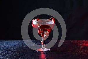 Beautiful transparent glass with red liquid and little snake which was curtailed in the form of heart against a dark background