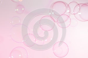 Beautiful transparent soap bubbles float on a pink texture background.