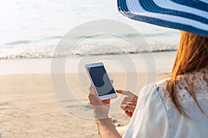 Beautiful traveler Asian woman  enjoys at tropical beach while using smart phone on vacation. Summer on beach concept. Close up,