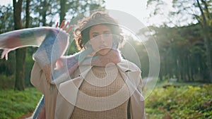 Beautiful traveler walking autumn park in scarf. Woman strolling wood closeup