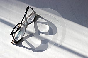 Beautiful trendy black round reading glasses on white wooden background and lens projection and reflection on the table