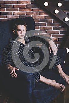 Beautiful trendy teen boy sitting on a chair at home