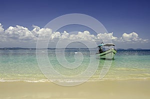 Beautiful tropical beach at Kapas Island, Malaysia. tourist boat anchored with blue sky background and crystal clear blue sea photo