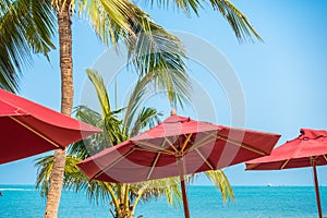 Beautiful tropical beach sea ocean with umbrella and chair around coconut palm tree on blue sky