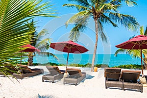 Beautiful tropical beach sea ocean with umbrella and chair around coconut palm tree on blue sky