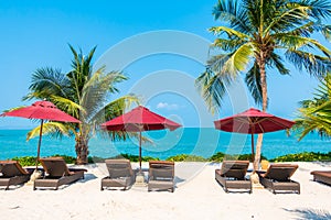 Beautiful tropical beach sea ocean with umbrella and chair around coconut palm tree on blue sky