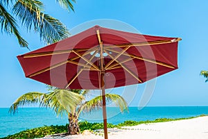 Beautiful tropical beach sea ocean with umbrella and chair around coconut palm tree on blue sky