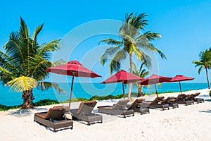 Beautiful tropical beach sea ocean with umbrella and chair around coconut palm tree on blue sky