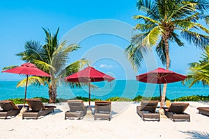 Beautiful tropical beach sea ocean with umbrella and chair around coconut palm tree on blue sky