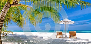 Beautiful tropical island scenery, two sun beds, loungers, umbrella under palm tree. White sand, sea view with horizon, idyllic