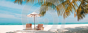 Beautiful tropical island scenery, two sun beds, loungers, umbrella under palm tree. White sand, sea view with horizon, idyllic