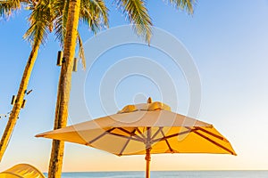 Beautiful tropical nature umbrella chair with palm tree around beach sea ocean at sunset or sunrise