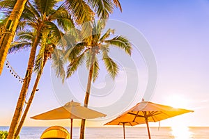 Beautiful tropical nature umbrella chair with palm tree around beach sea ocean at sunset or sunrise