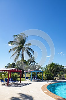 Beautiful tropical resort with swimming pool, sun-loungers and palm trees during a warm sunny day, vacations in Cuba