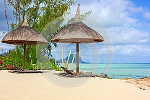 Beautiful tropical white sandy beach with exotic tropical plants,beach umbrellas and sunbeds on traditional mauritian style with a