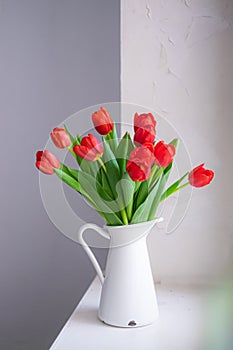 Beautiful tulip bouquet in white vase on white rustic background. lifestyle close up