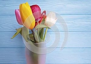 Beautiful tulips fresh vase, lovely on a blue wooden background