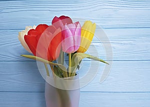 Beautiful tulips vase, on a blue wooden background