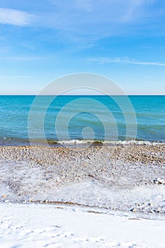 Beautiful turquoise colored water along Lake Michigan shoreline in winter - vertical