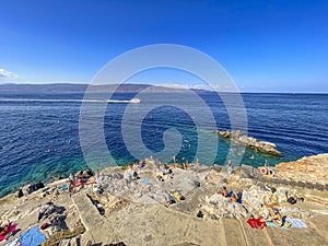 Beautiful turquoise rocky seascape with a famous swimming place full of tourists and visitors near Hydronetta coctail bar in Hydra