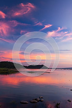 Beautiful twilight sky above a tropical lake, gently light pink clouds against the blue sky at dusk