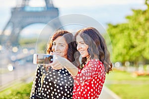 Beautiful twin sisters taking selfie in front of Eiffel Tower