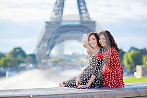 Beautiful twin sisters taking selfie in front of Eiffel Tower