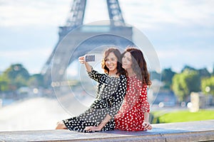 Beautiful twin sisters taking selfie in front of Eiffel Tower