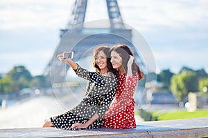 Beautiful twin sisters taking selfie in front of Eiffel Tower