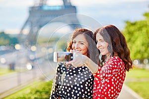 Beautiful twin sisters taking selfie in front of Eiffel Tower