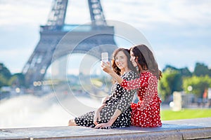 Beautiful twin sisters taking selfie in front of Eiffel Tower