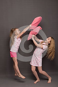 Beautiful two girls in pink pajamas play before going to bed