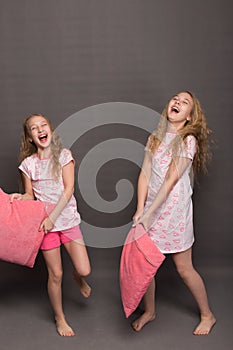 Beautiful two girls in pink pajamas play before going to bed