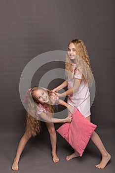 Beautiful two girls in pink pajamas play before going to bed