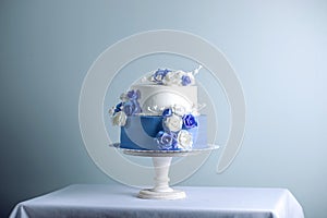 Beautiful two tiered white and blue wedding cake decorated with flowers sugar roses. Concept of elegant holiday desserts