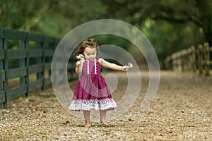 Beautiful two year old girl with a purple dress running and jumping with happiness.