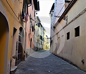Beautiful and typical street, with the facades of the most distant buildings illuminated by the setting sun and a white one at the
