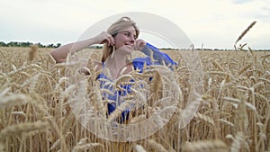 Beautiful Ukrainian woman wearing dress in Ukrainian national flag colours, blue and yellow, at wheat field in morning