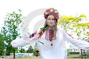 beautiful Ukrainian young woman tender girl in a large red wreath of bright pink white red flowers braiding ribbons in