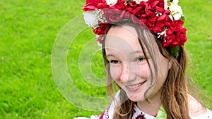 beautiful Ukrainian young woman tender girl in a large red wreath of bright pink white red flowers braiding ribbons in