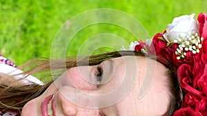 beautiful Ukrainian young woman tender girl in a large red wreath of bright pink white red flowers braiding ribbons in