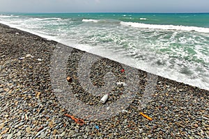 Beautiful unspoiled dark pebble stones beach with garbage, mostly plastic, washed out. Ocean littering concept